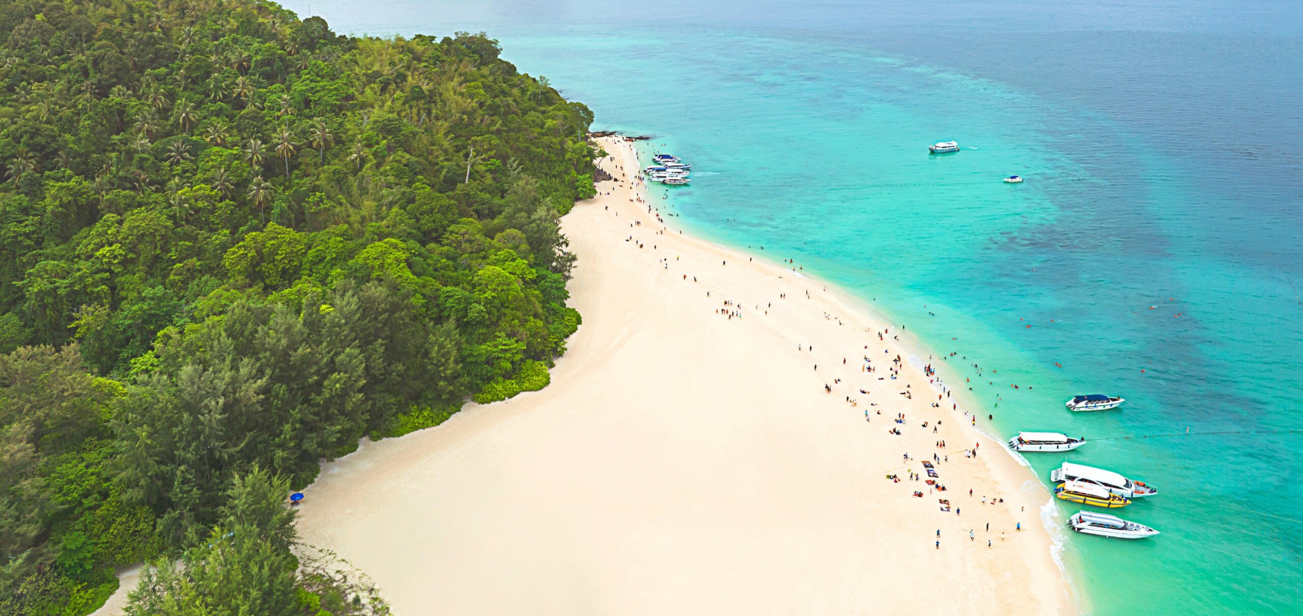 Bird 's eye view of summer tropical islands in the ocean as white sand beach with tourists and turquoise water
