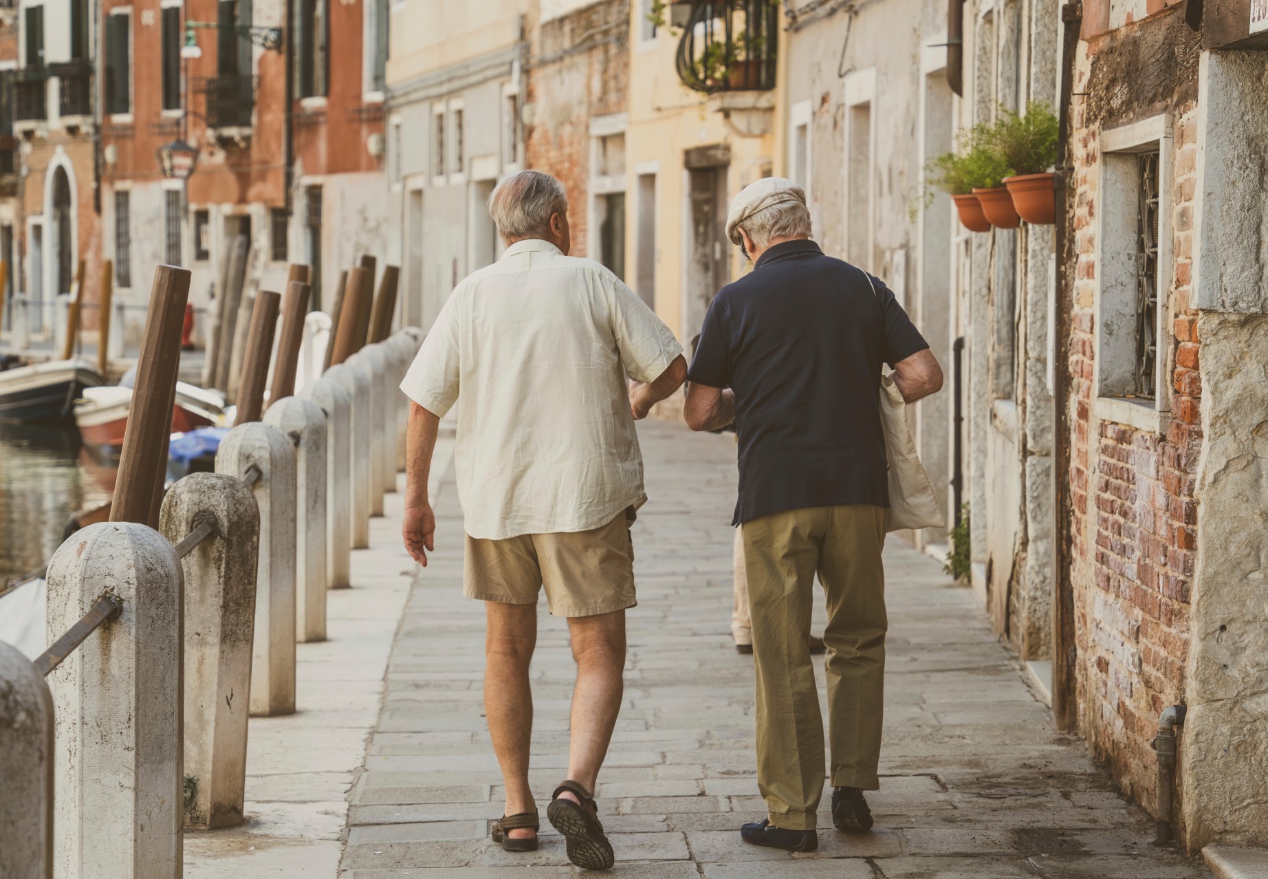 Two italian senior men walking on the cobblestone narrow streets in Venice, Italy
