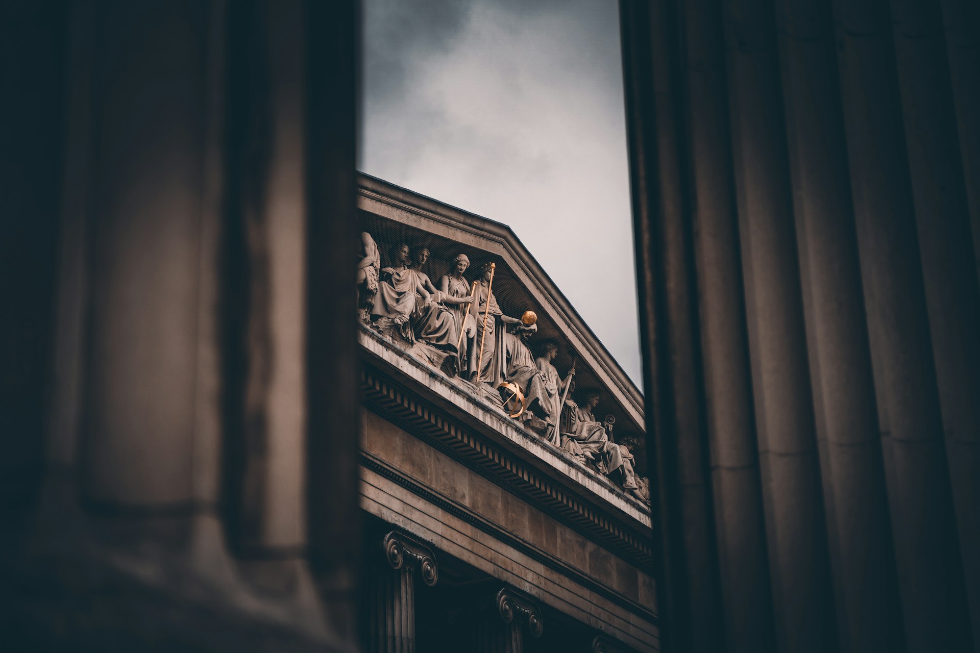 Historic neoclassical building with classical sculptures framed by large stone columns