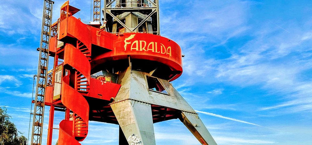 Crane Hotel Faralda Amsterdam red industrial crane with spiral staircase and Faralda logo against a bright blue sky