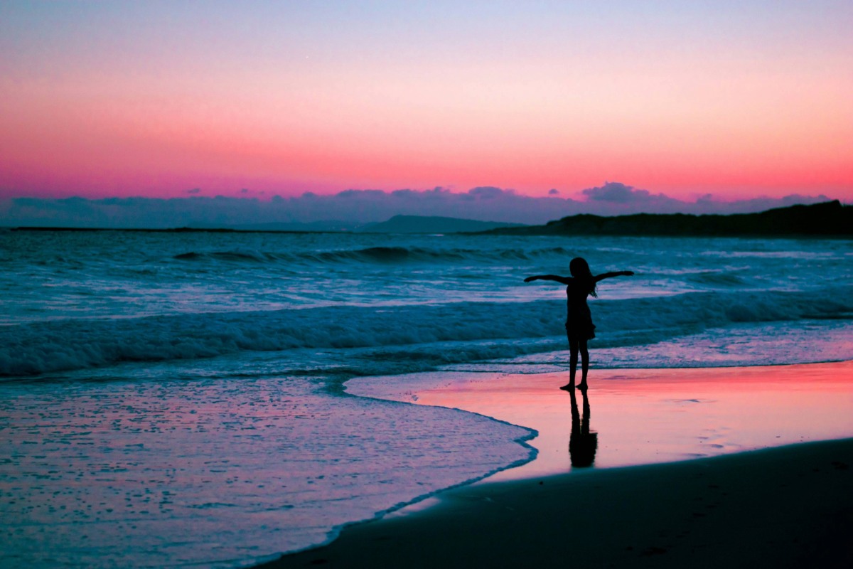 Solo traveler standing on beach during sunset reflecting on solo travel journey