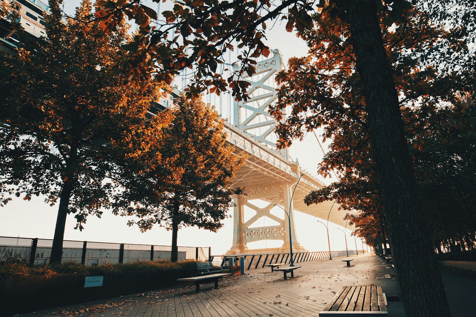 Urban walkway beneath large bridge representing East and West Coast city vibes