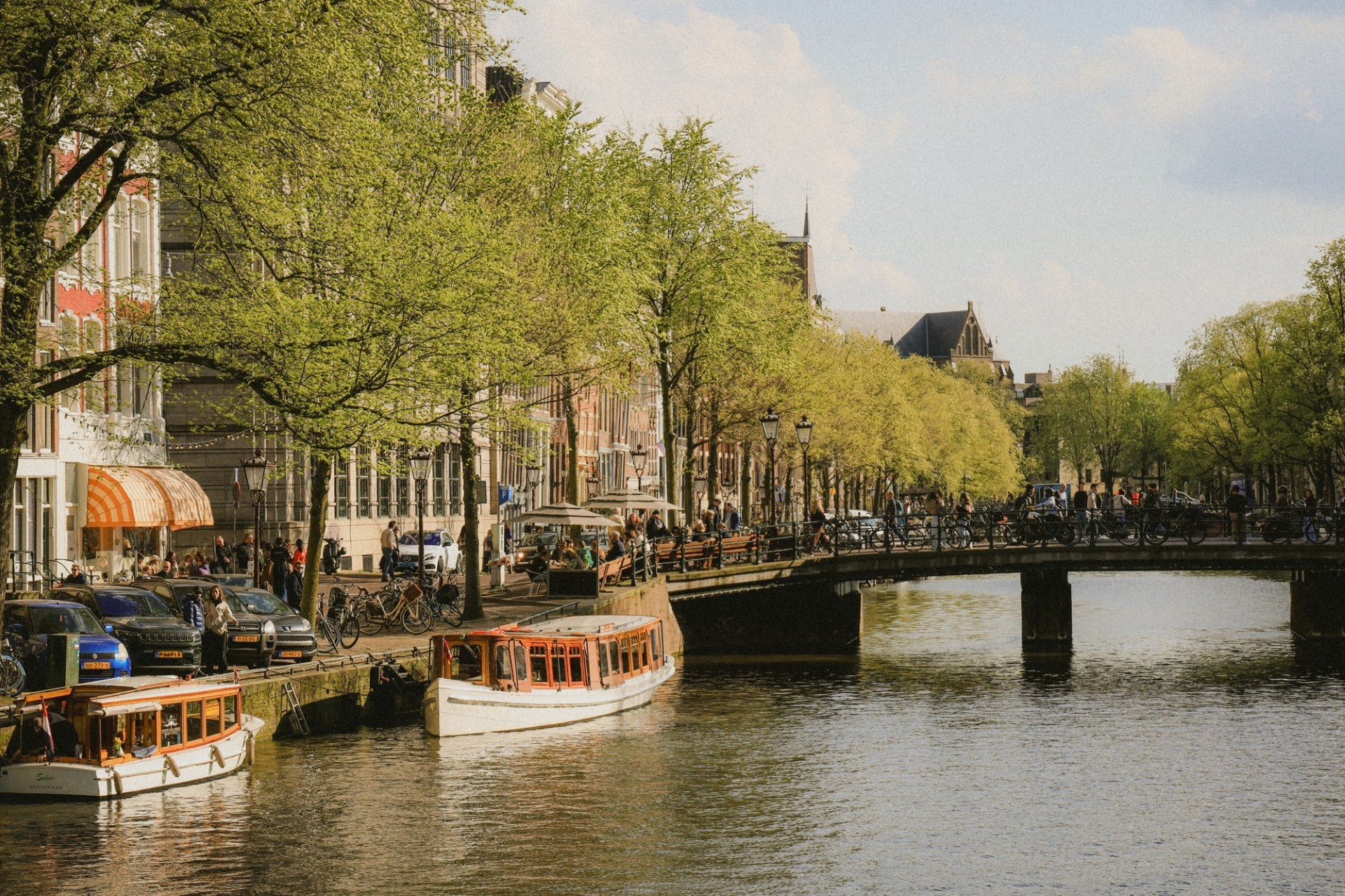 Amsterdam canal with boats, bridges, and outdoor cafés in the Netherlands
