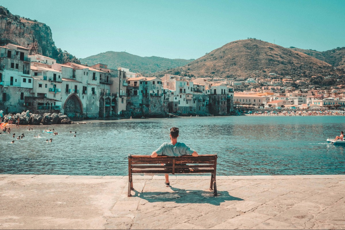Traveler sitting beside scenic Italian coastal village overlooking the water