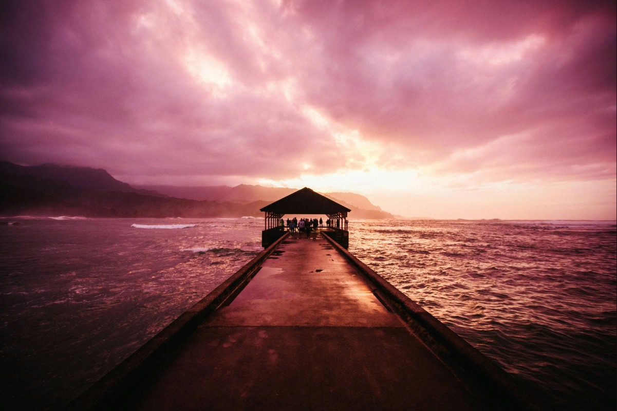 Hawaiian beach sunset with ocean pier for an article about the best beaches in Hawaii.