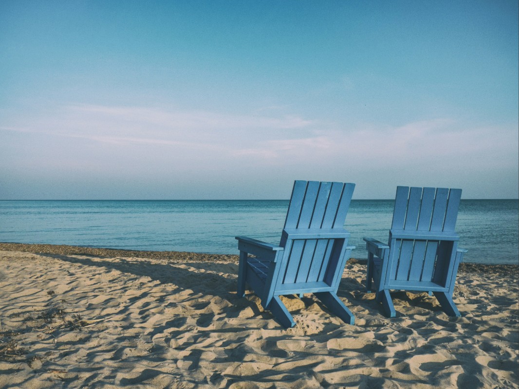 Adirondack chairs on a quiet beach overlooking calm water in a peaceful American beach town