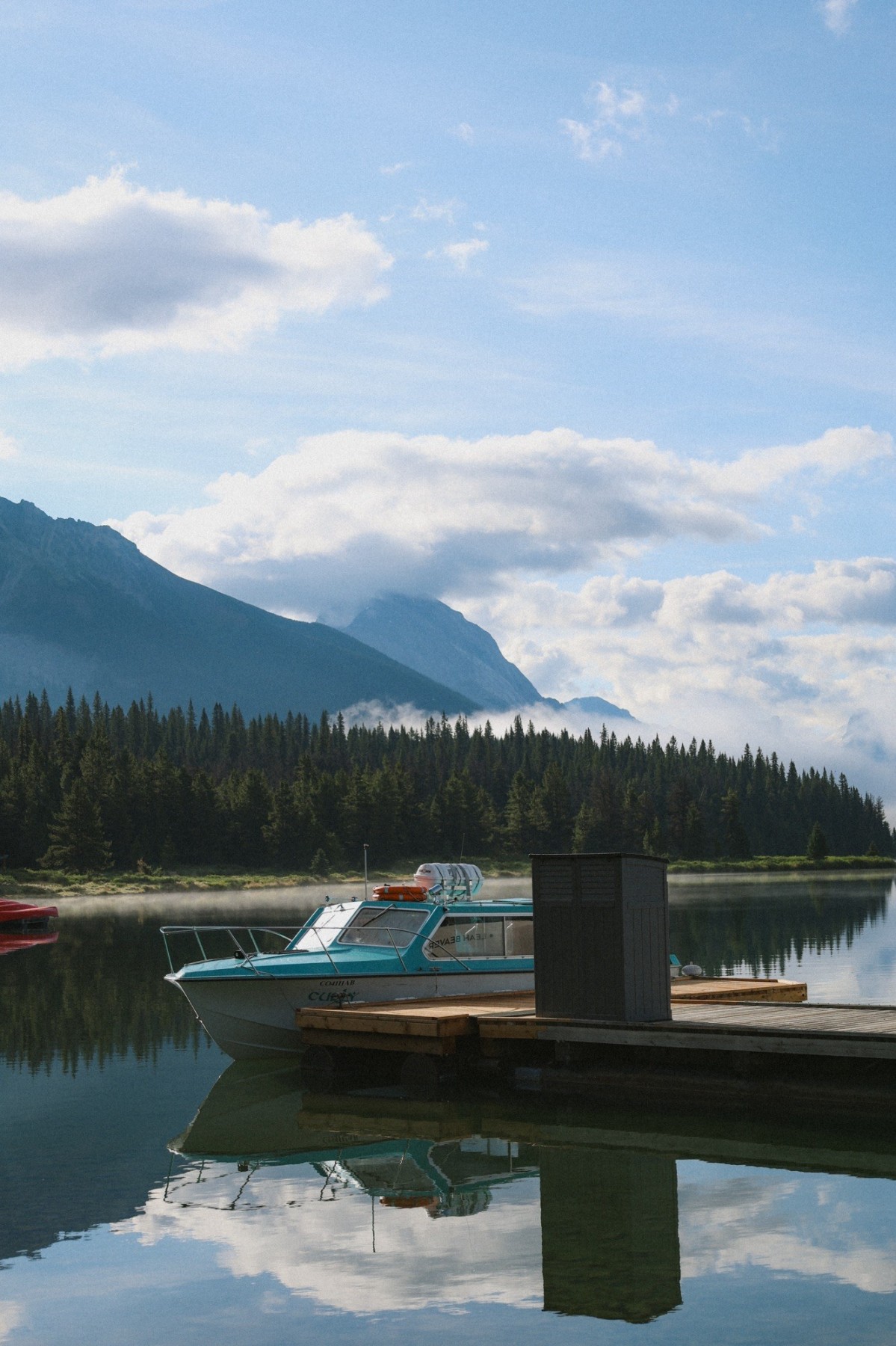 Boat docked on a peaceful mountain lake surrounded by forests and mountains during a meaningful travel experience